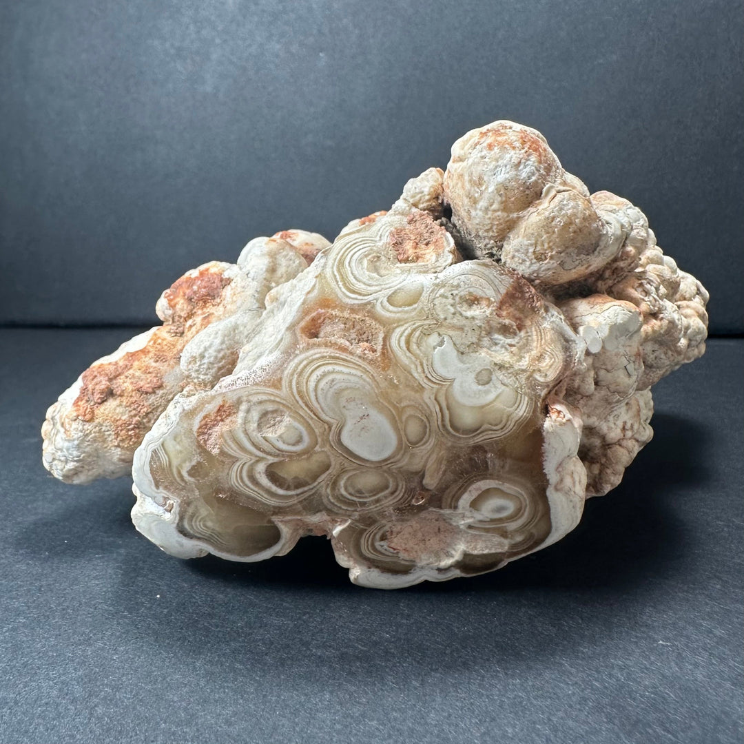 Banded onyx-like stalactite rock with pale white, tan, and rust-colored streaks