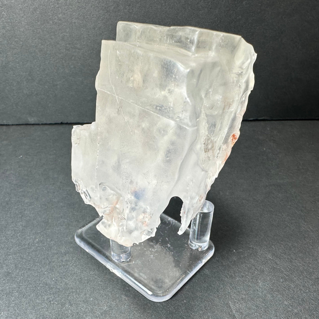 Colorless cubic fluorite mineral specimen with orange inclusions, side view on clear base