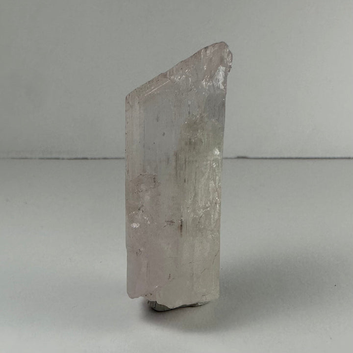 Terminated pale kunzite crystal, tall prismatic shape, translucent with etched texture