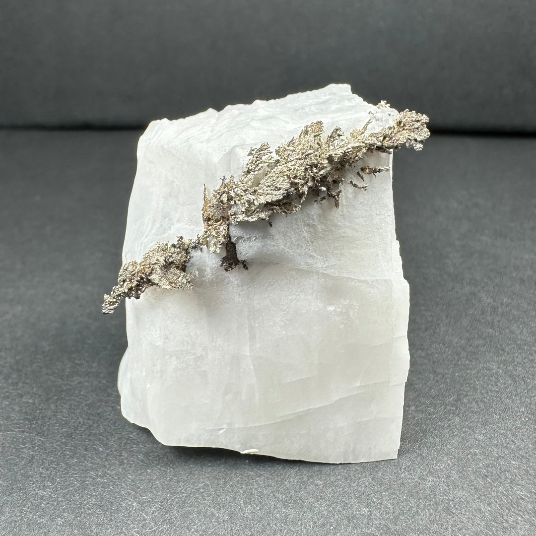 White calcite block with branching silver-gray dendrite detail across the surface