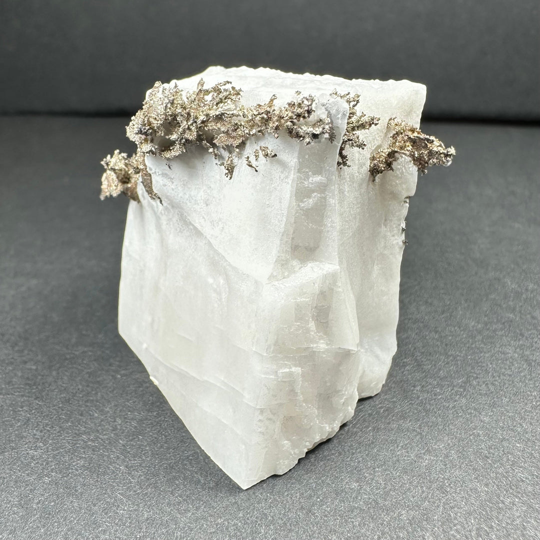 White calcite block with clusters of silver-gray dendritic crystal on top edge