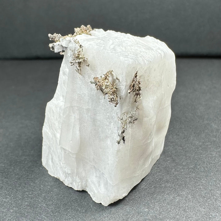 White calcite specimen with three silver-gray dendrite sprays down one side