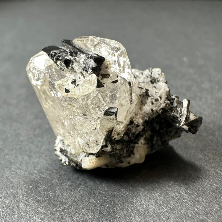 Mineral crystal specimen with clear white quartz and black tourmaline clusters amid matrix.