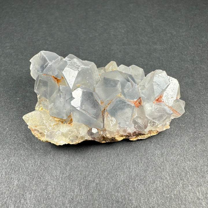 Celestite crystal cluster on tan matrix with translucent light blue cubes and orange flecks