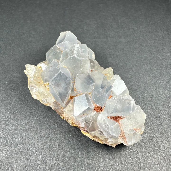 Celestite crystal cluster on tan matrix with pale blue translucent crystals and tiny orange spots