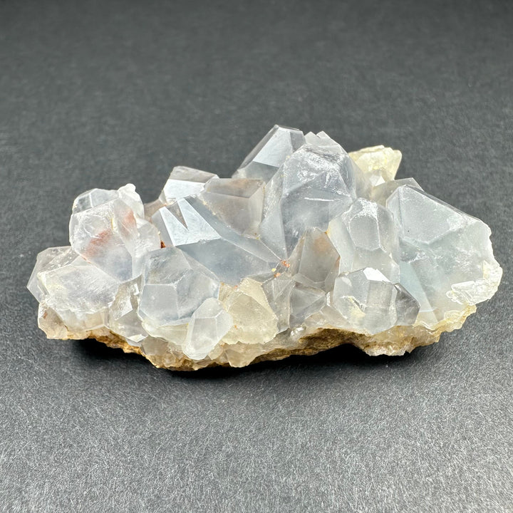 Celestite crystal cluster on tan matrix featuring many translucent pale blue prismatic crystals