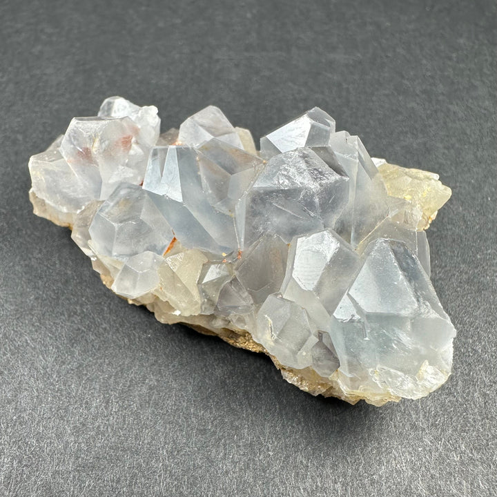 Celestite crystal cluster on light tan matrix with translucent blue-white prismatic crystals