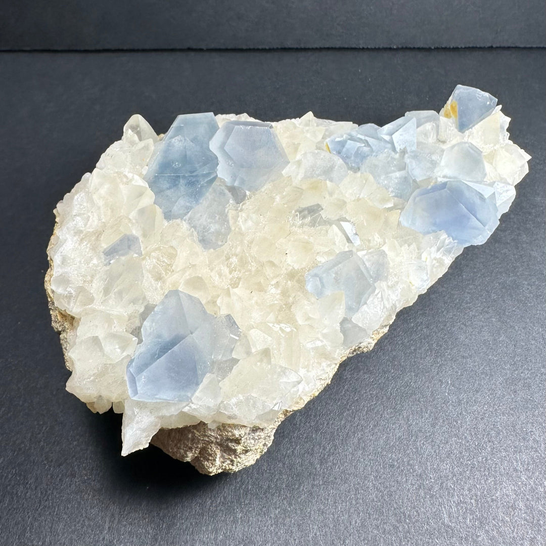 Celestite and calcite crystal specimen with blue crystals over creamy white rock