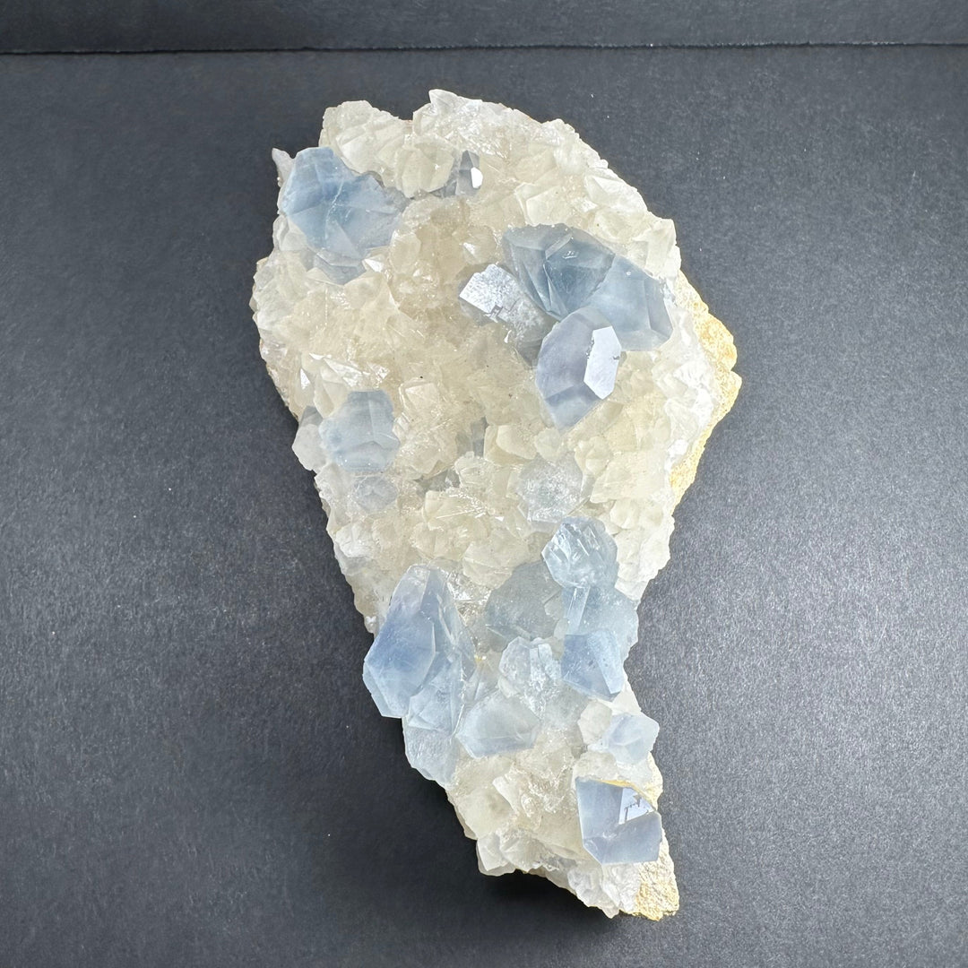 Small triangular crystal cluster with light blue translucent pieces on white calcite