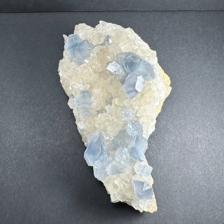 Small triangular crystal cluster with light blue translucent pieces on white calcite