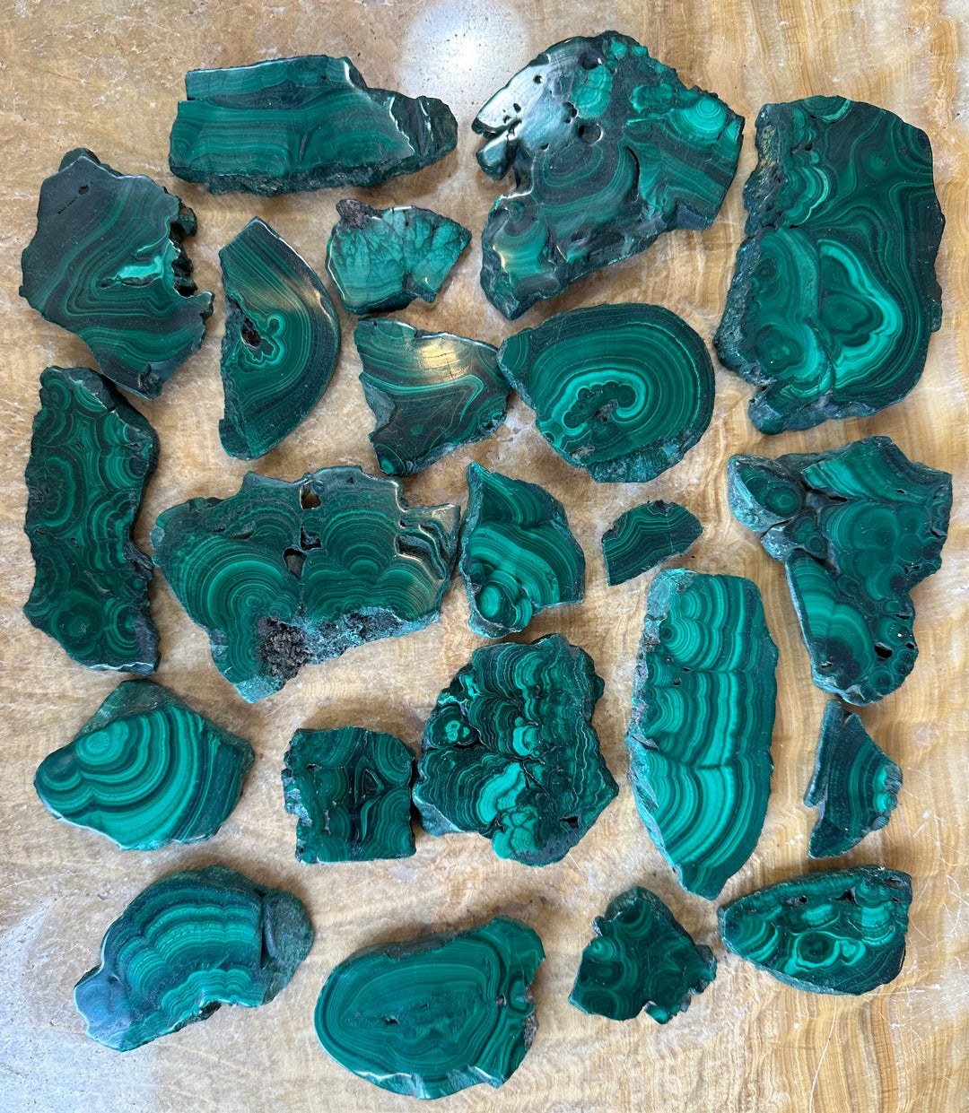 Polished malachite slice stones in teal-green with swirling banded patterns.