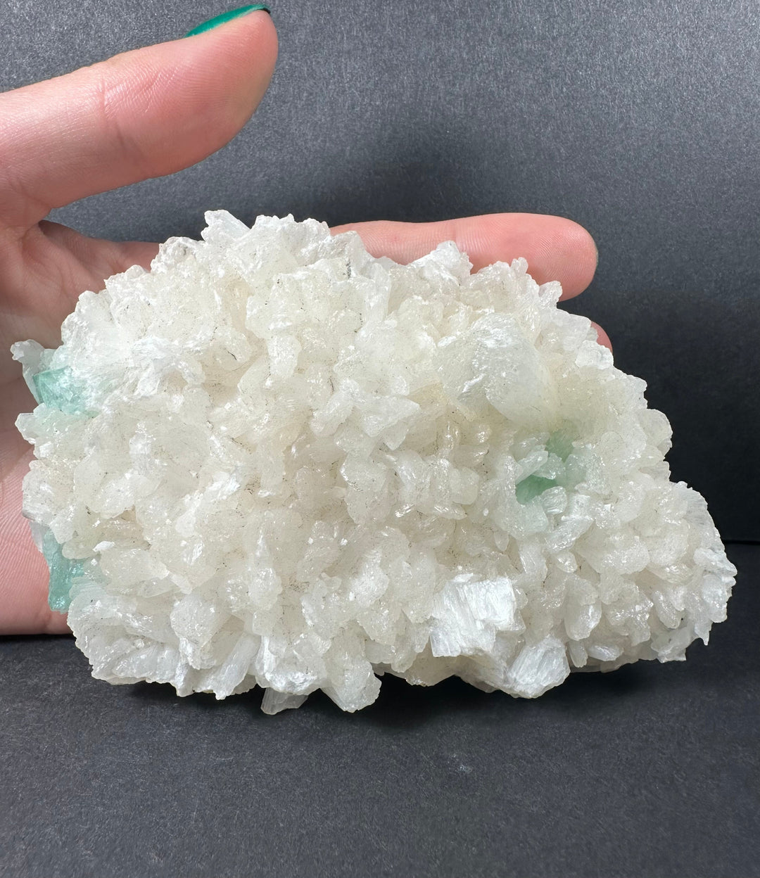 Hand-held mineral crystal cluster with white crystals and light aqua-green matrix