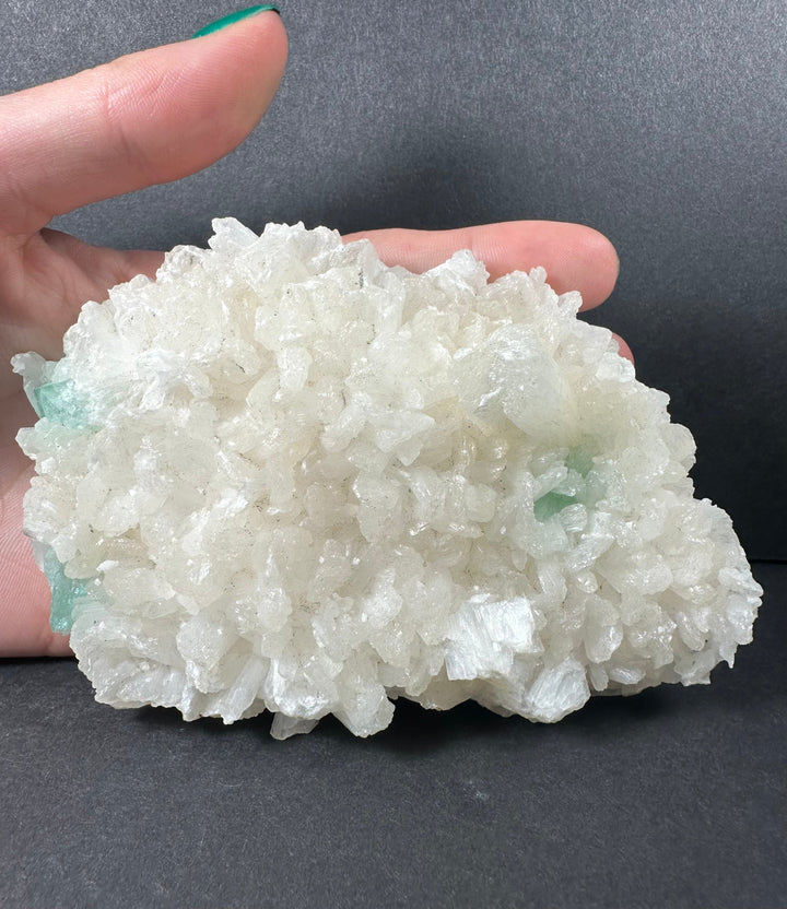 Hand-held mineral crystal cluster with white crystals and light aqua-green matrix