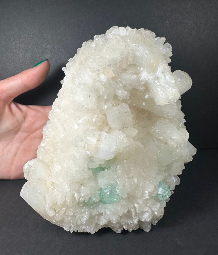 White crystal specimen with pale green points, held in hand