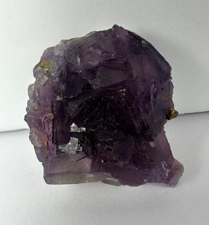 Purple cubic fluorite cluster on dark rock matrix, faceted crystals and rough base