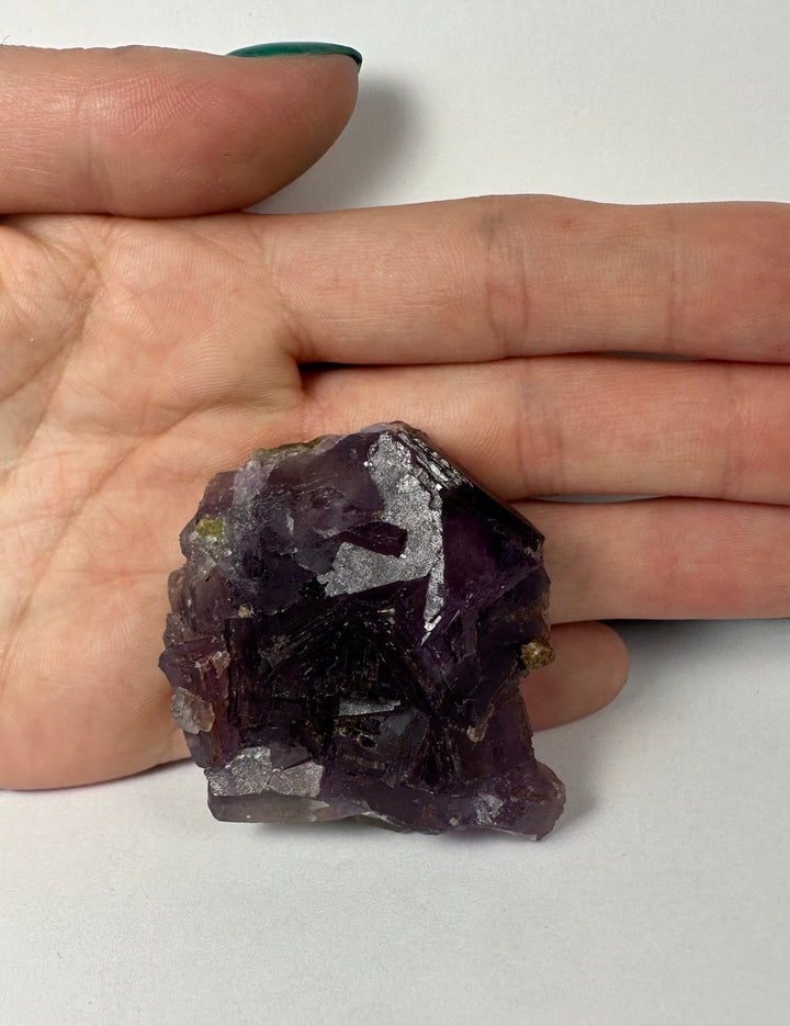Purple fluorite on matrix held in hand, cubic faceted crystals