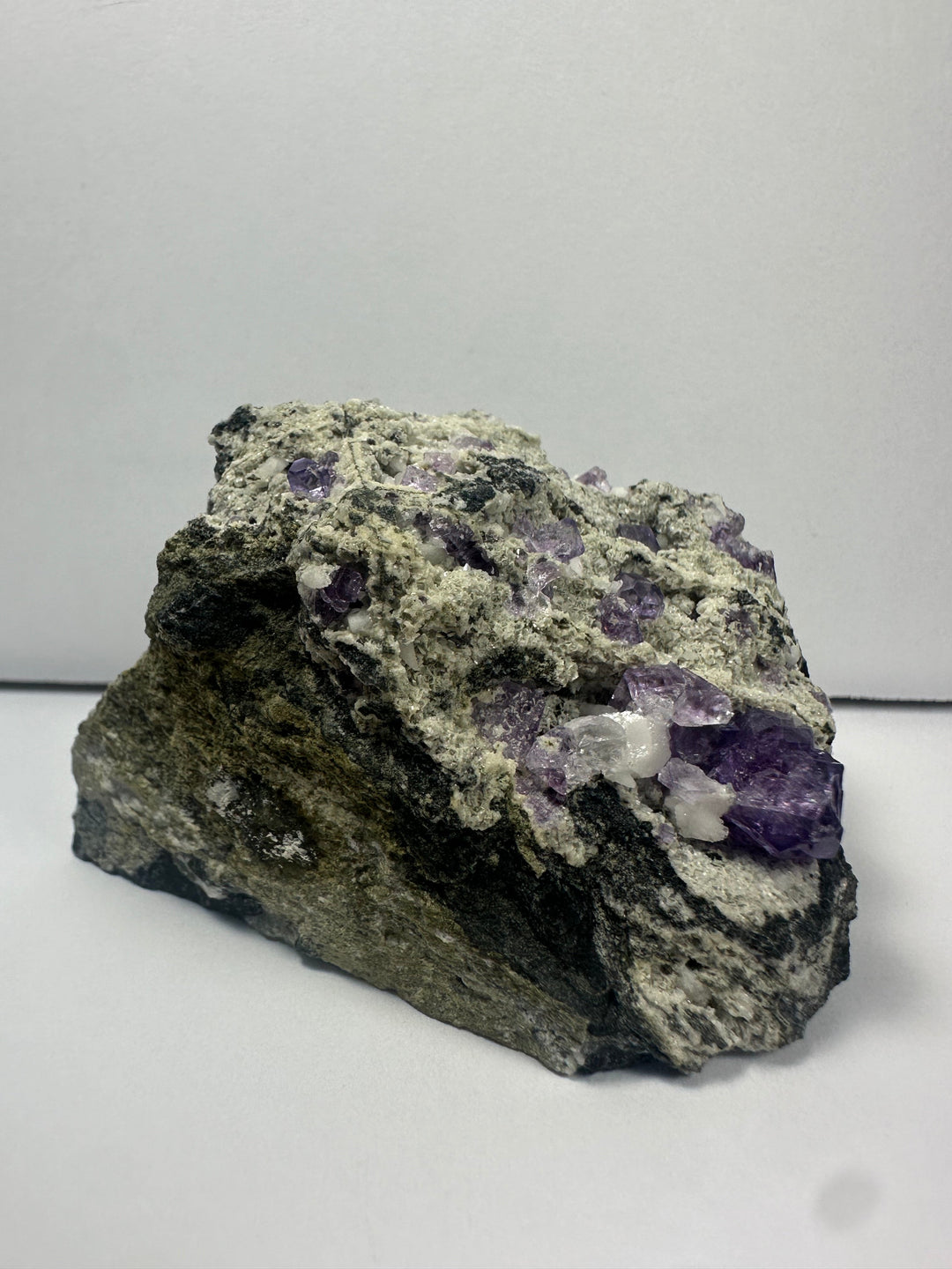 Purple fluorite clusters on dark gray matrix rock with rough texture