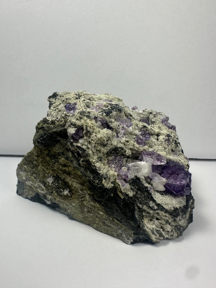 Purple fluorite clusters on dark gray matrix rock with rough texture