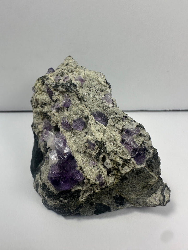 Purple fluorite crystal clusters on gray rock matrix, angled view