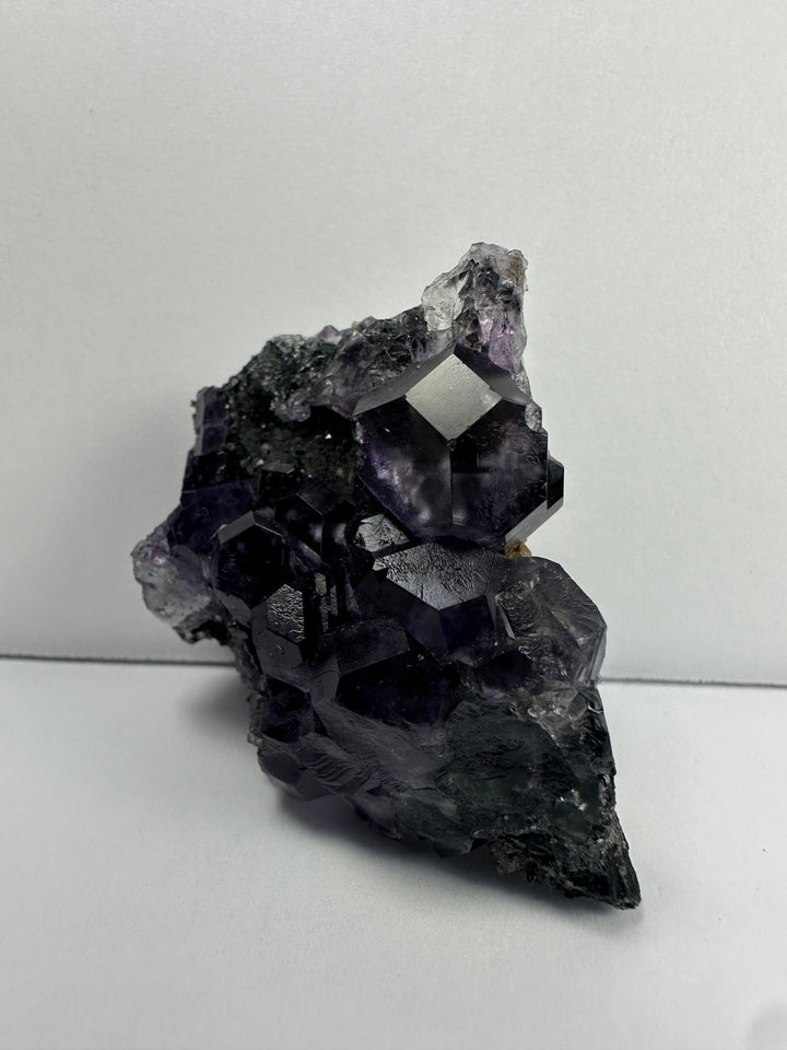 Purple fluorite crystals on dark matrix base, angled close view