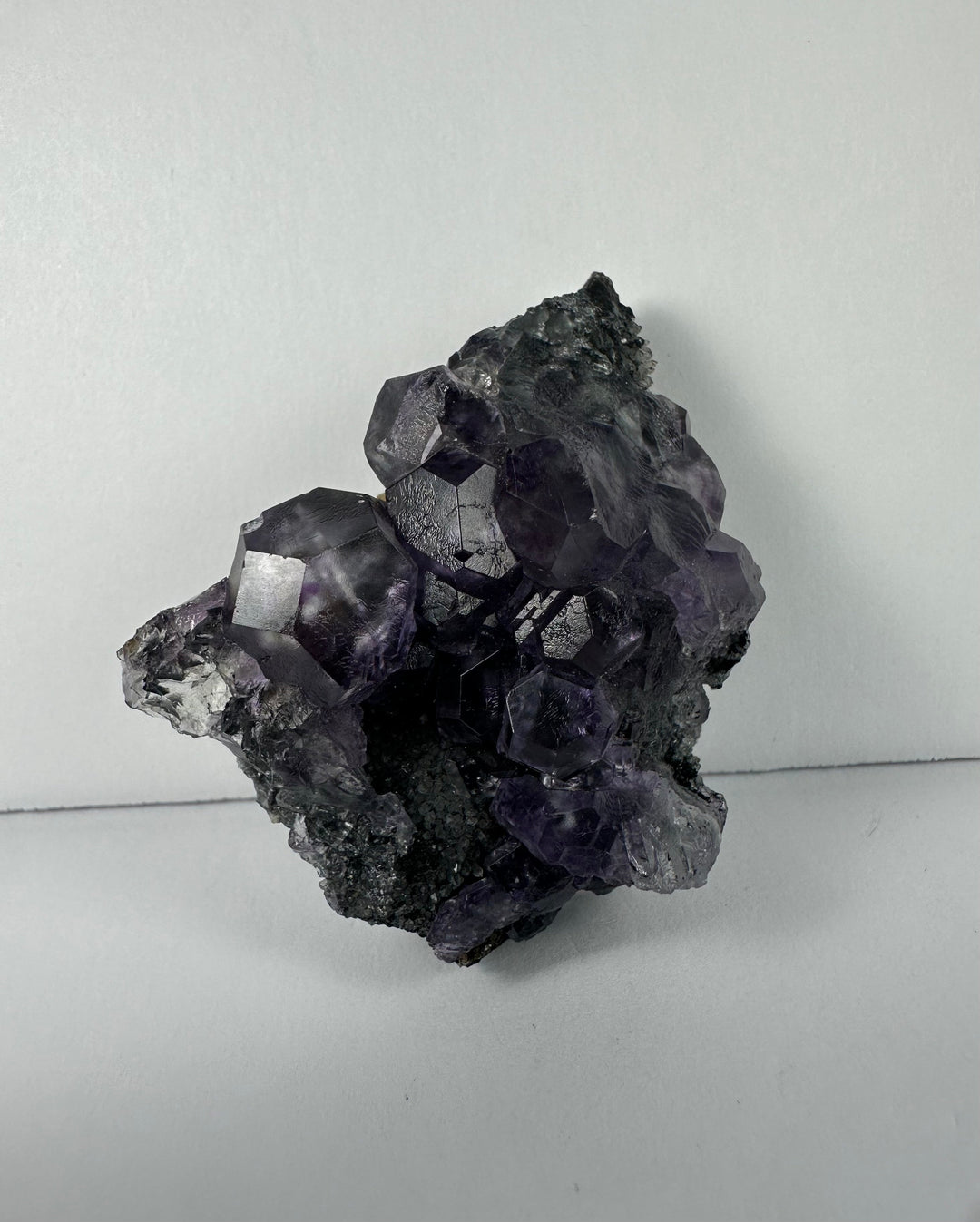 Purple fluorite crystal cluster on dark matrix rock, compact upright view