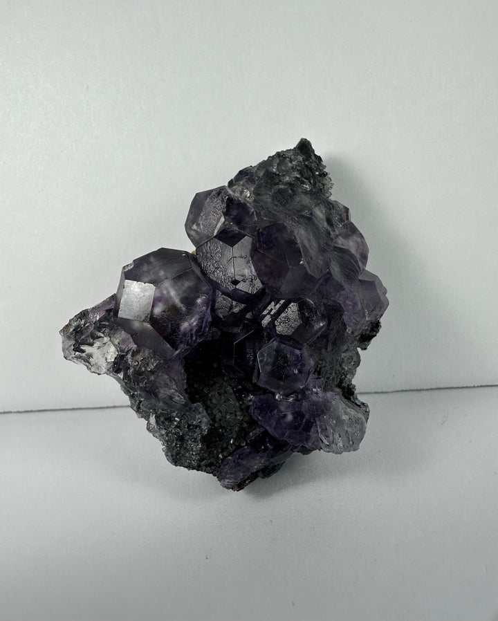 Purple fluorite crystal cluster on dark matrix rock, compact upright view