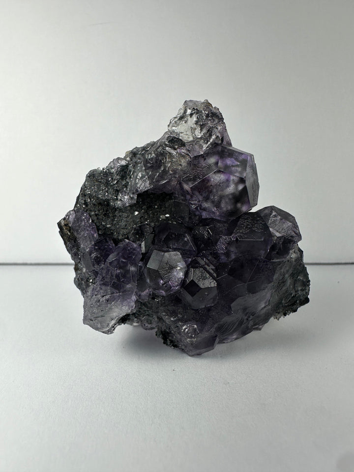 Purple-tinted fluorite crystals on dark mineral matrix specimen
