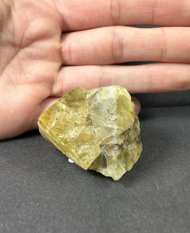 Yellow fluorite crystal cluster held in palm, faceted translucent yellow and clear faces