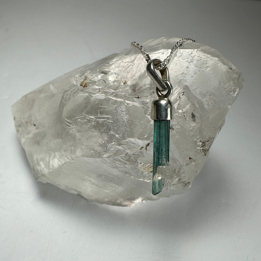 Green tourmaline pencil pendant with silver-toned chain and loop bail
