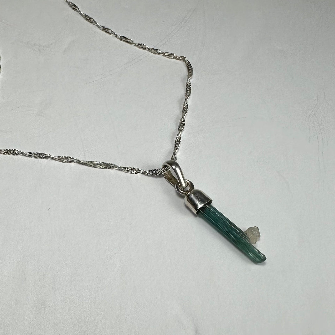 Teal-green tourmaline pencil pendant on silver-toned link chain