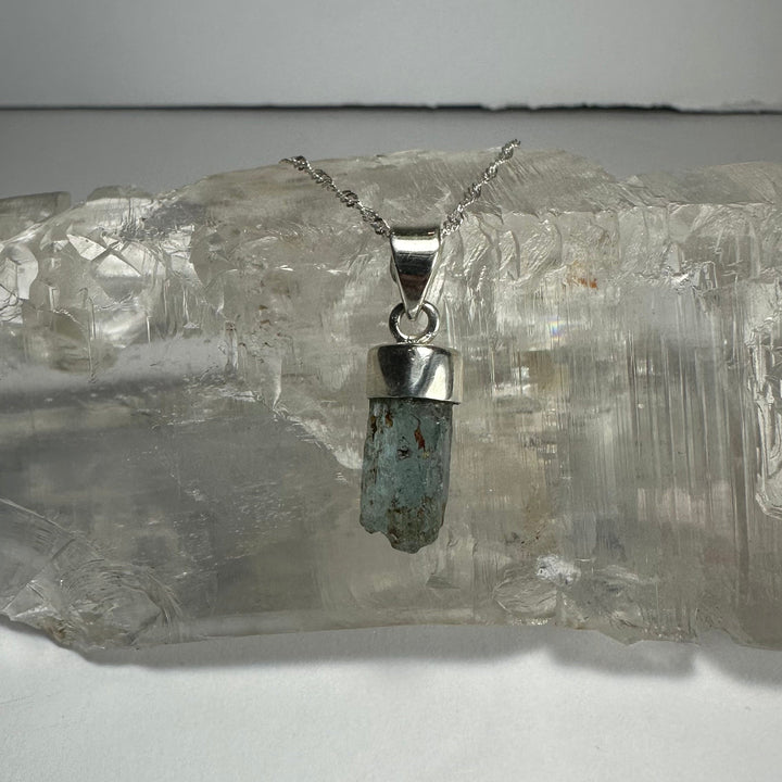 Aquamarine beryl pendant with faceted blue-green stone on silver-tone chain