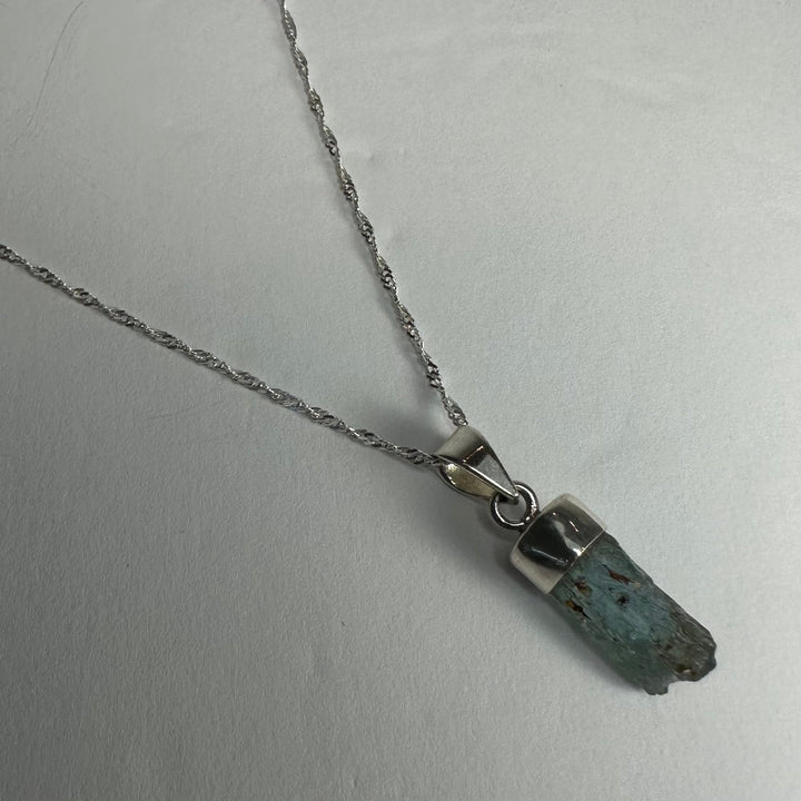 Aquamarine beryl pendant with faceted dark blue stone and silver-tone bail