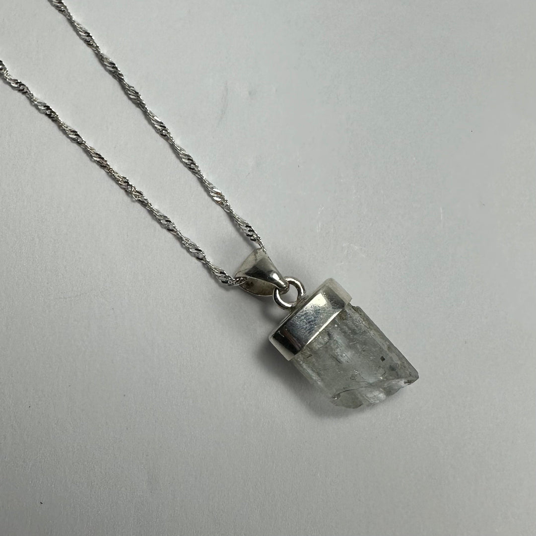 Aquamarine beryl pendant with pointed clear pale stone on silver-tone chain