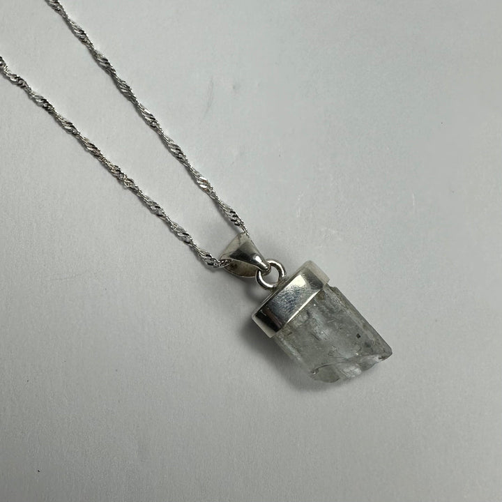 Aquamarine beryl pendant with pointed clear pale stone on silver-tone chain
