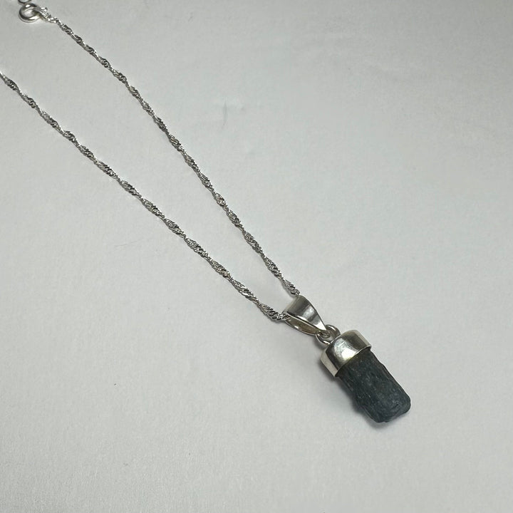Aquamarine beryl pendant with pointed dark blue stone on silver-tone chain