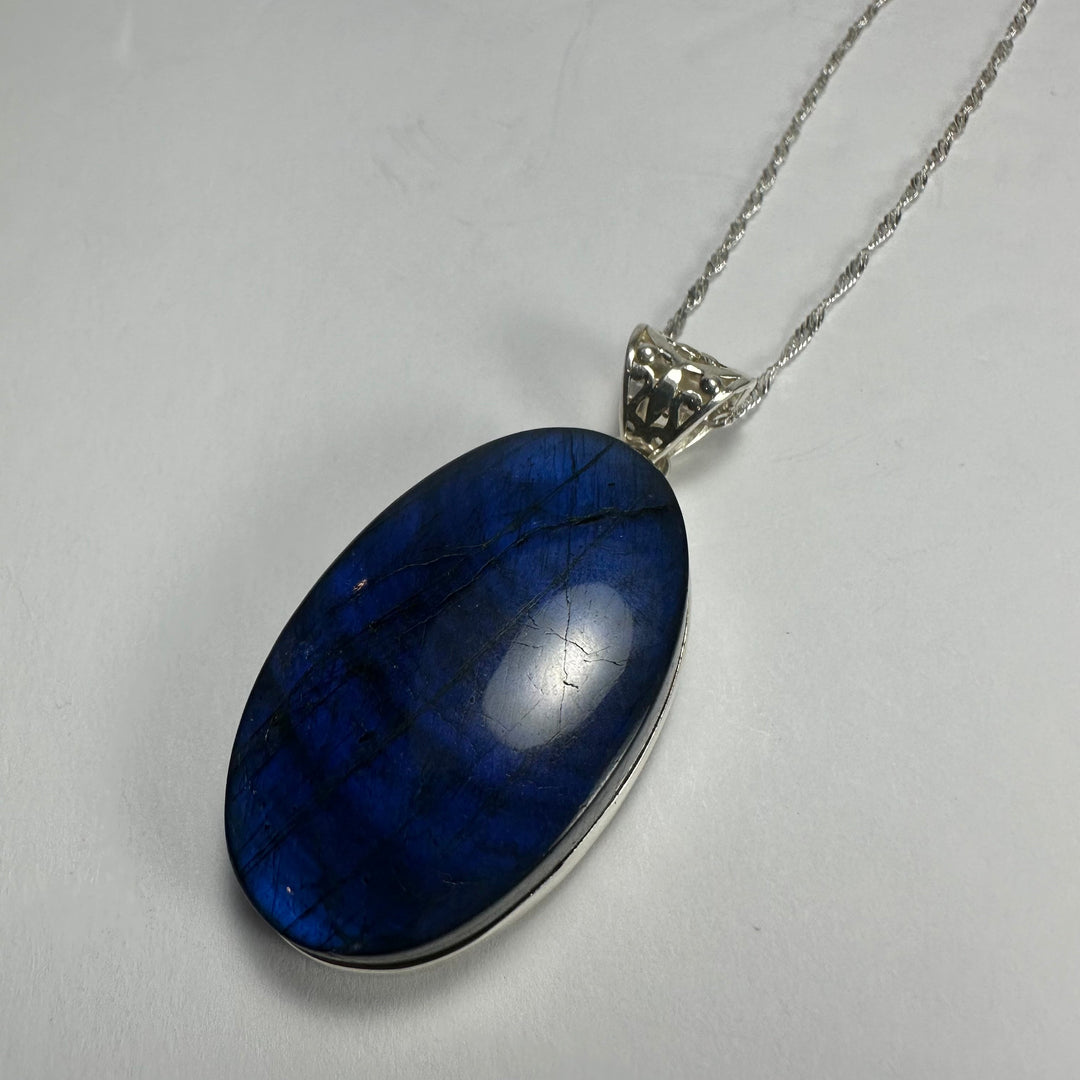Oval blue labradorite pendant on silver-tone chain with ornate bail