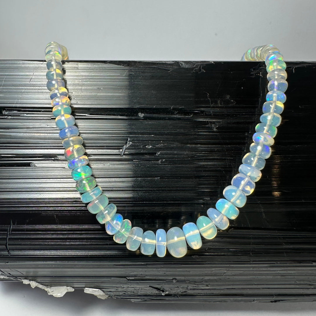 Graduated opal-like bead necklace with round iridescent beads, arranged in a U shape