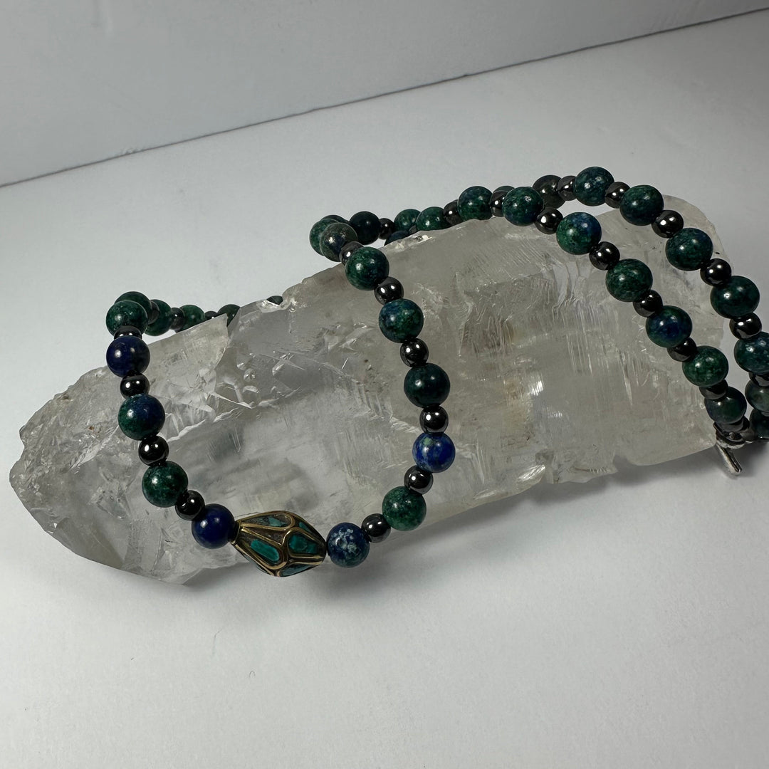 Beaded necklace with dark green and navy beads and brass frame pendant with turquoise inlay
