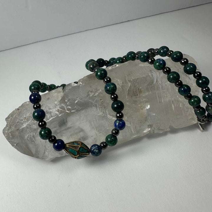 Beaded necklace with dark green and navy beads and brass frame pendant with turquoise inlay