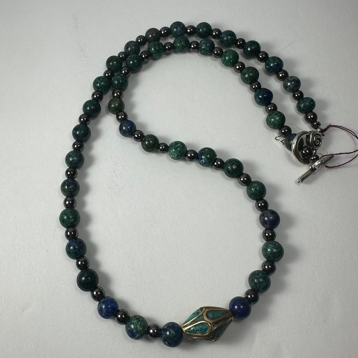 Beaded necklace with dark green and navy round stones, brass-and-turquoise centerpiece