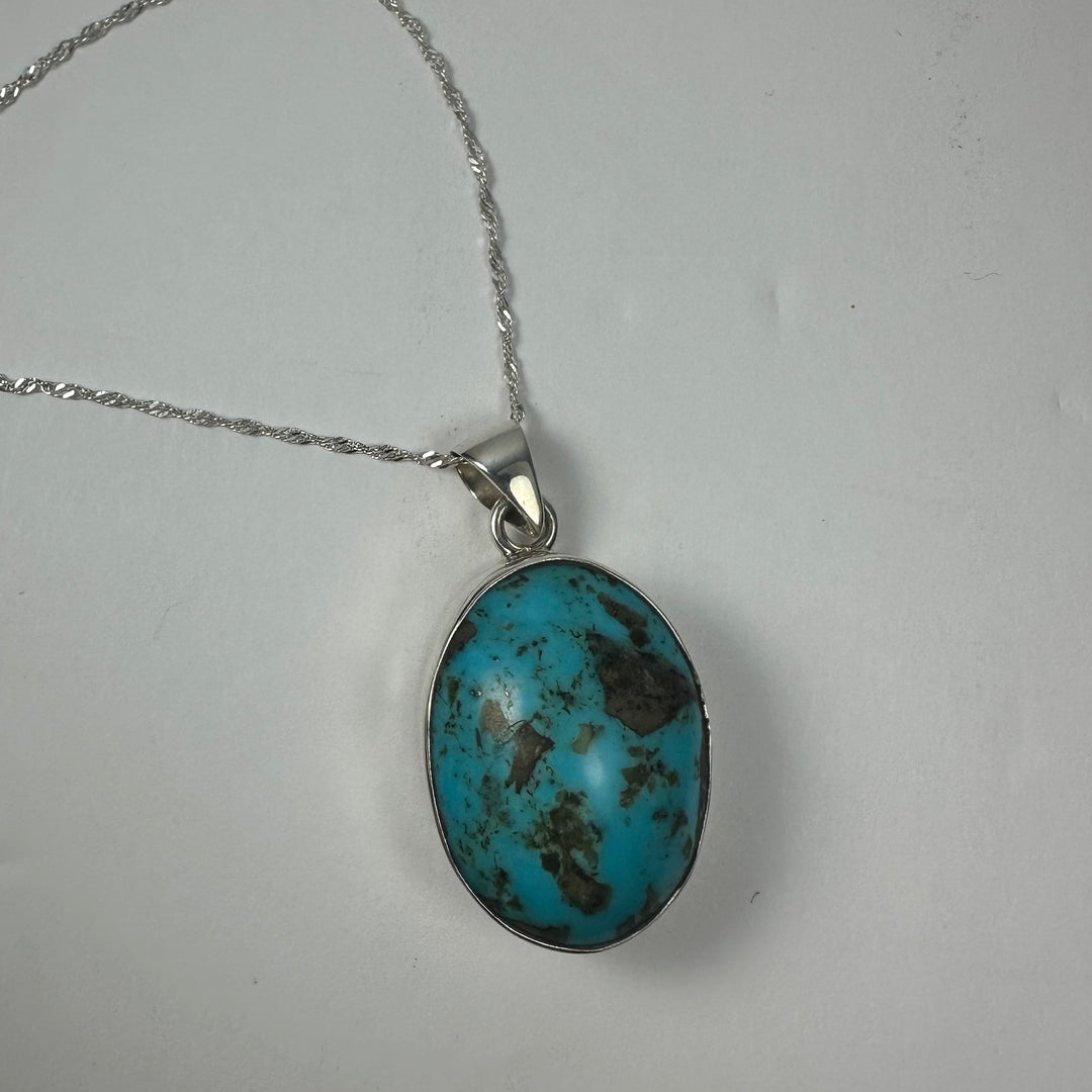 Oval turquoise stone pendant on silver chain with loop bail