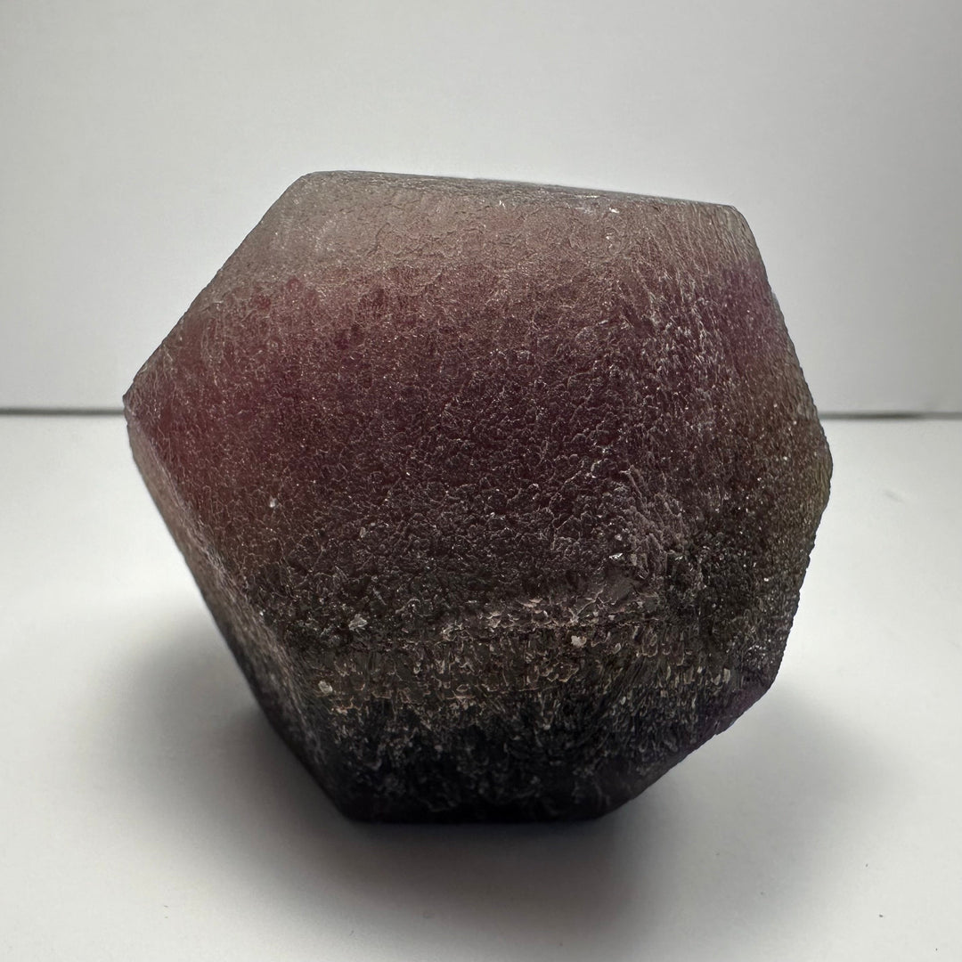 Fluorite dodecahedron, purple-brown rough crystal with pointed facet edges
