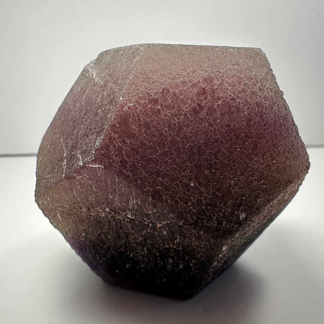 Fluorite dodecahedron, dark purple rough crystal with faceted surface