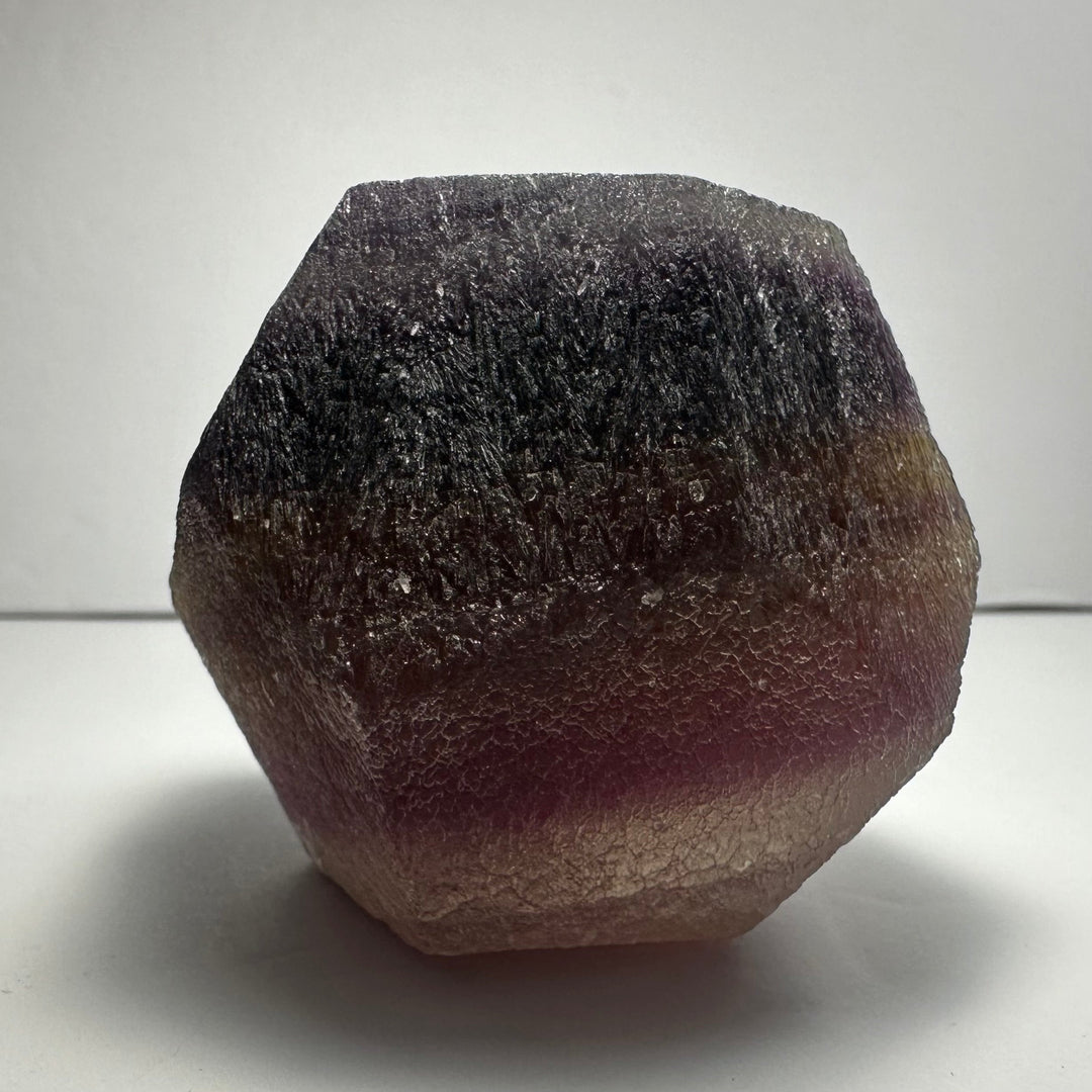 Fluorite dodecahedron, deep maroon stone with rough textured surface and facets