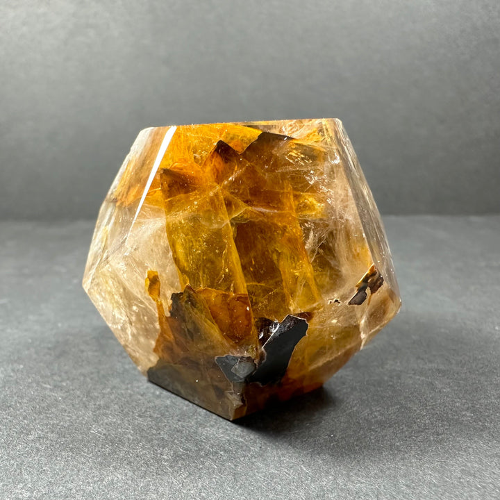 Yellow hematoid quartz dodecahedron carving with clear facets and dark mineral inclusions