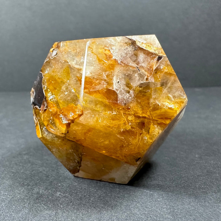 Yellow hematoid quartz dodecahedron carving with translucent facets and dark flecks