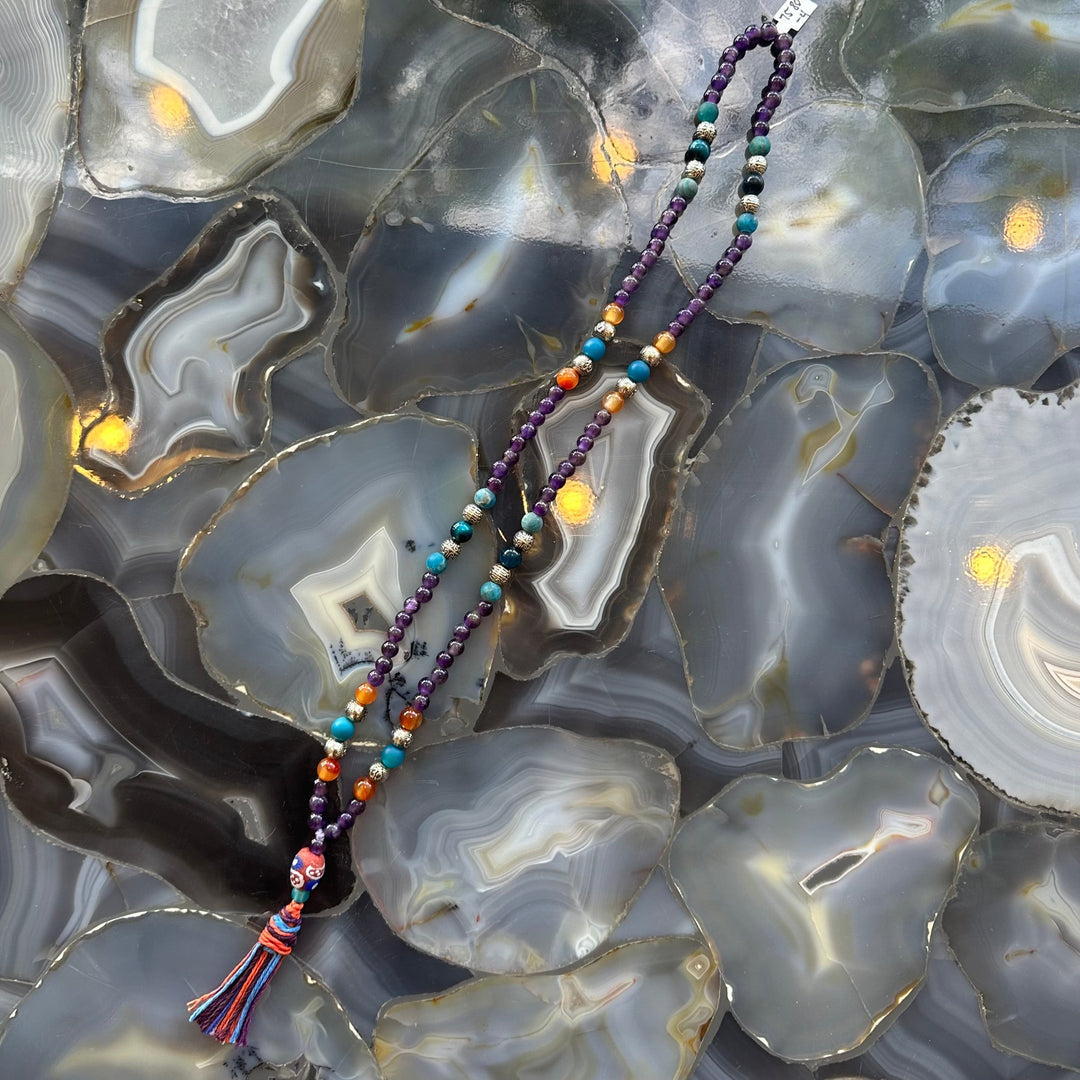Amethyst mala necklace with purple, teal, and orange mixed stone beads; tassel pendant.