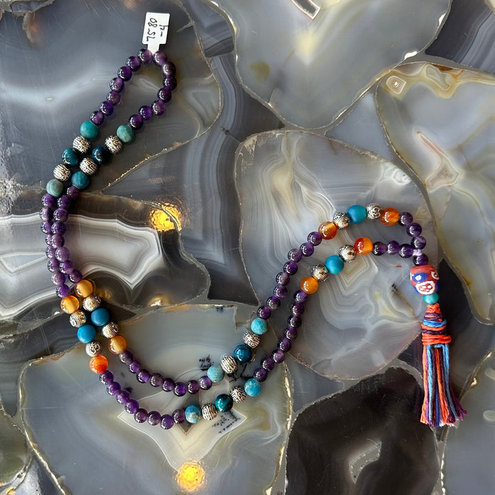 Mala necklace with layered strands of purple beads, turquoise accents, orange spacer beads.