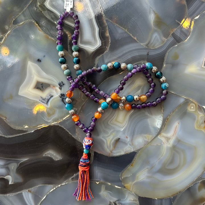 Mala necklace with purple amethyst beads, turquoise and orange stones, multicolor tassel charm.