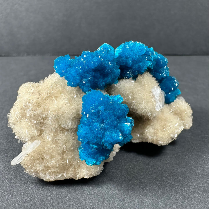 Cavansite and stilbite cluster on pale beige matrix with vivid blue crystals